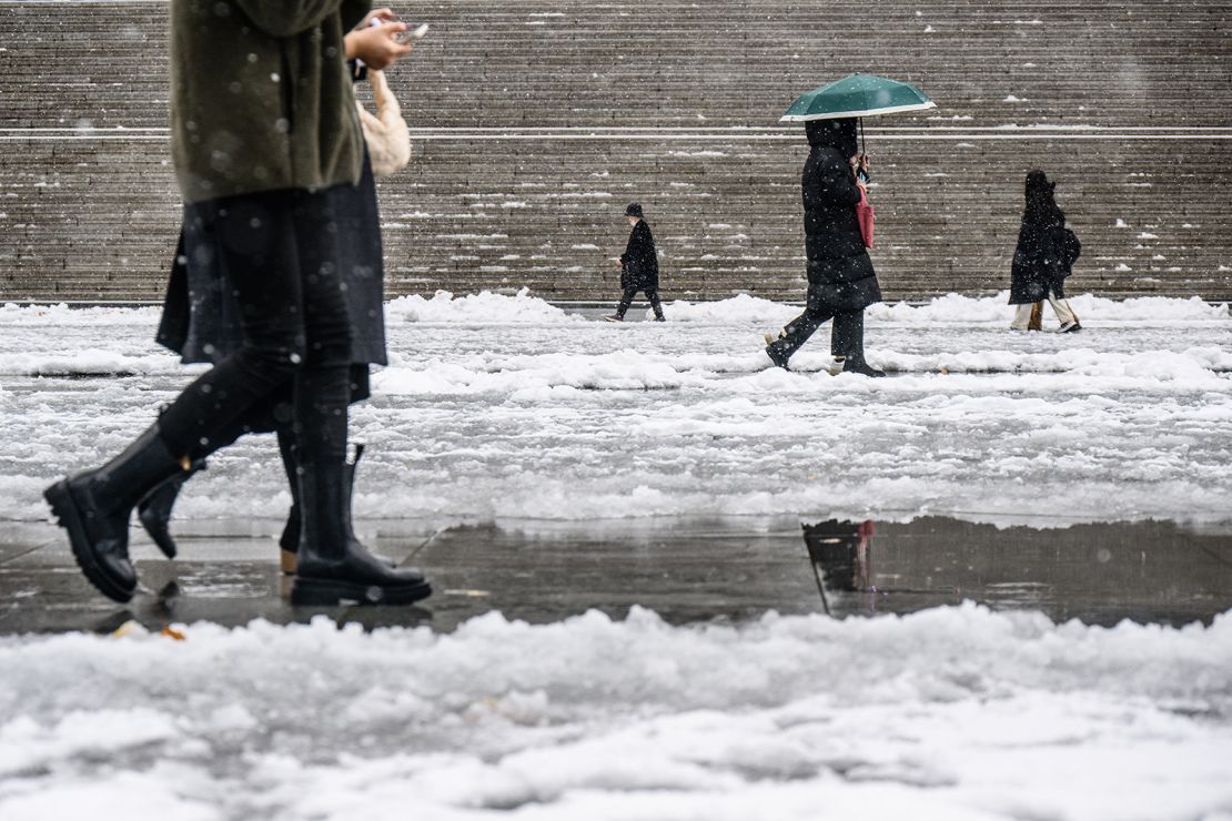 People walk along Gwanghwamun Square amid heavy snowfall in central Seoul.